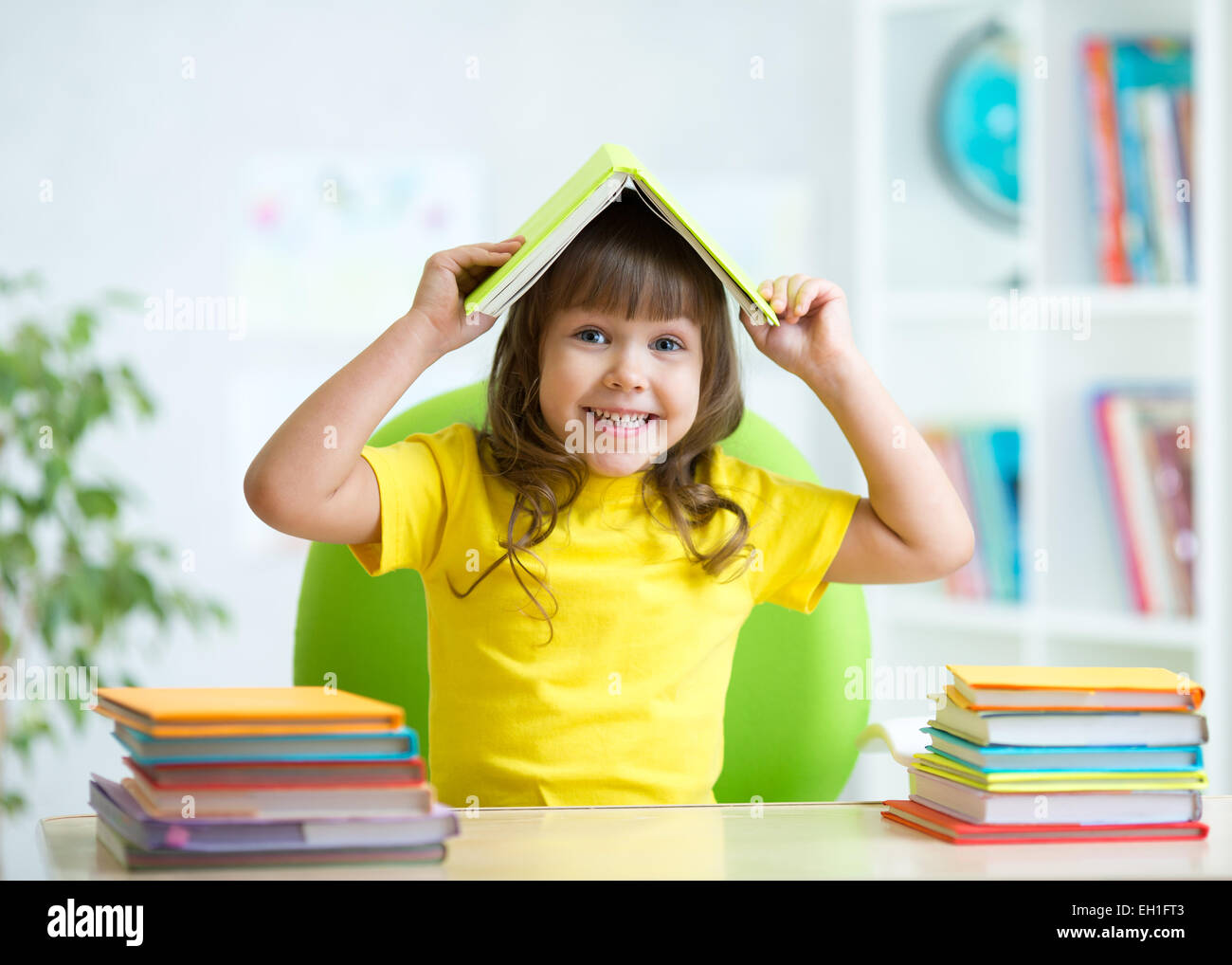 Studente bambino con un libro sulla sua testa Foto Stock