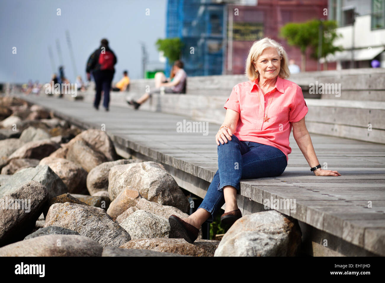 A piena lunghezza Ritratto di felice donna senior rilassante sulla pedana a seashore Foto Stock