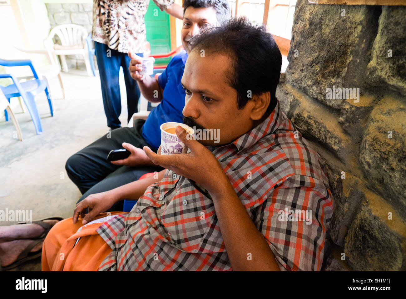 Un locale indiana uomo beve chai come si prende una pausa per il te'. Uno di India preferito di tempi passati Foto Stock