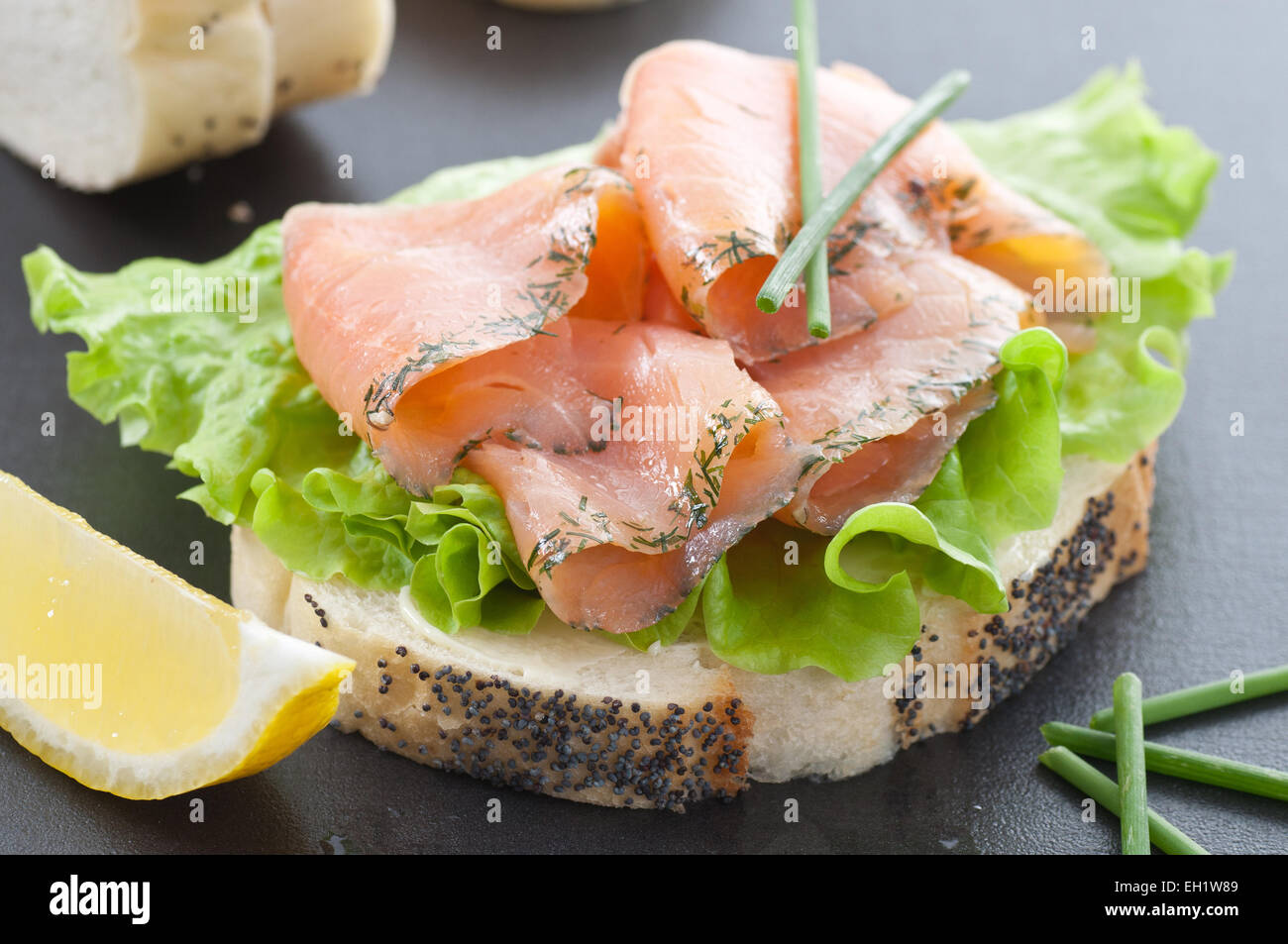 Gravlax affettata sul pane bianco, lattuga, erba cipollina e limone. Foto Stock