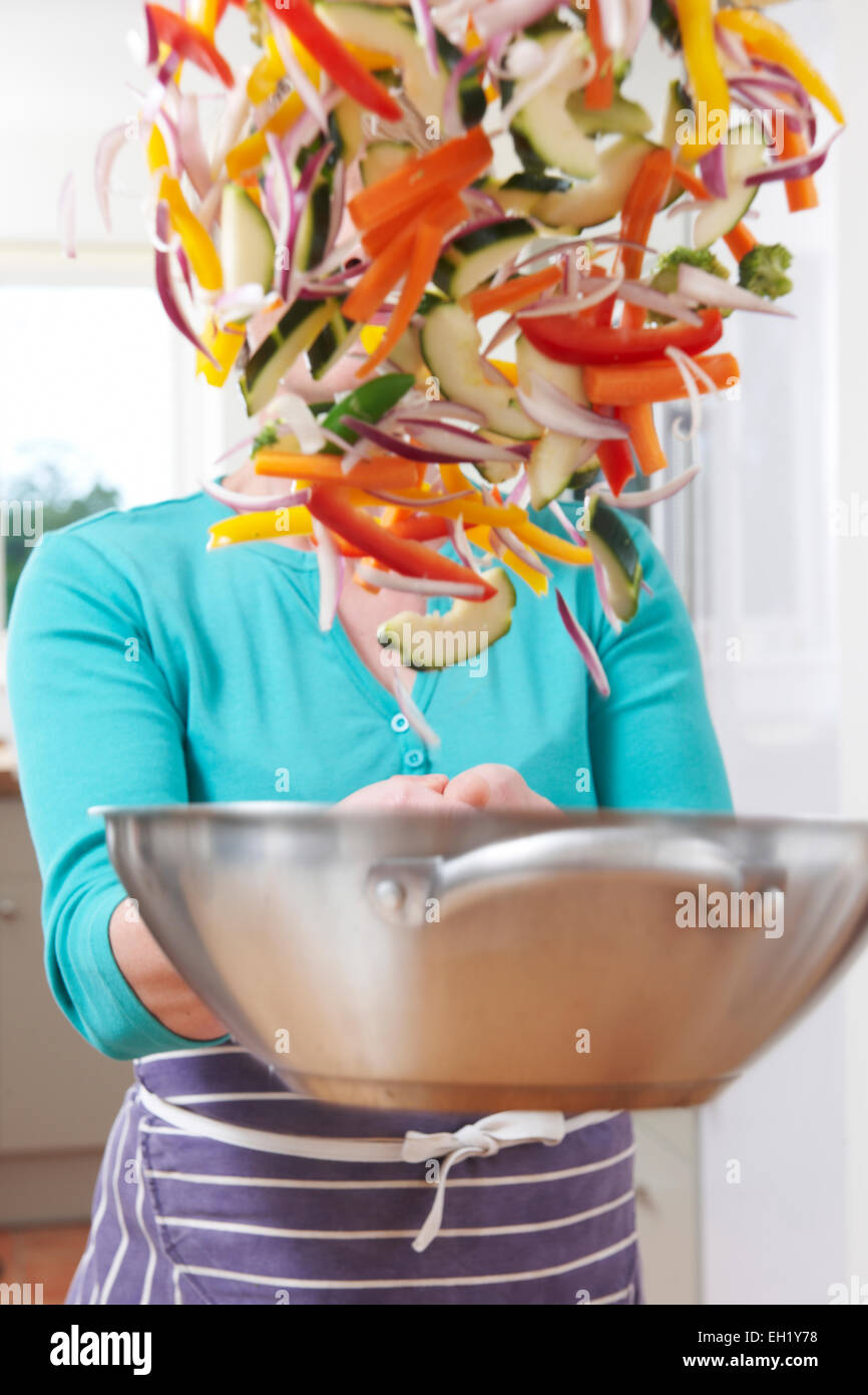 Cuoca Tossing verdure in padella oscurando il suo volto Foto Stock