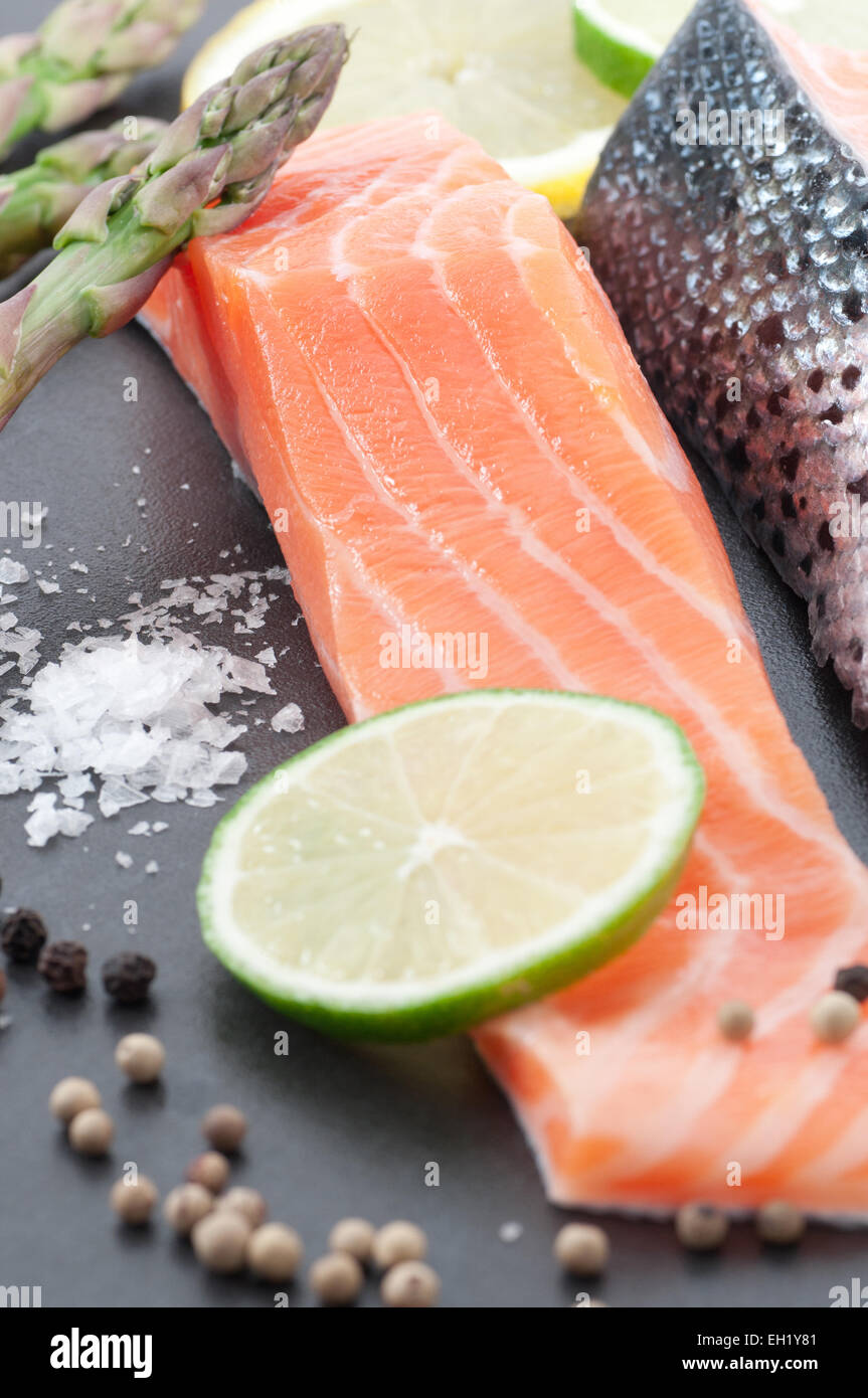 Porzione di materie salmone con asparagi freschi, limone, sale marino e pepe. Foto Stock
