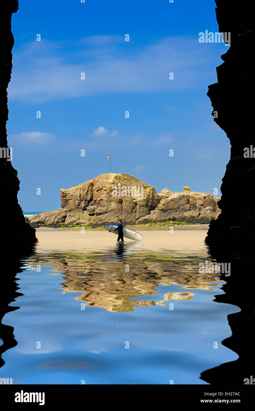 Un surfista a piedi attraverso una creata digitalmente la piscina di acqua Perranporth beach,Cornwall,Inghilterra England Regno Unito. Foto Stock