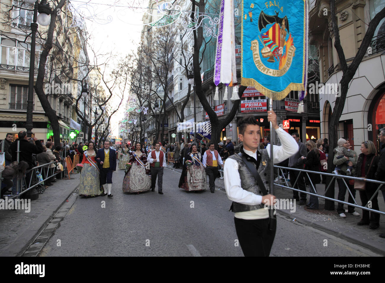 Un giovane uomo nel tradizionale Las Fallas Festival dress tenendo un banner che portano una processione Foto Stock