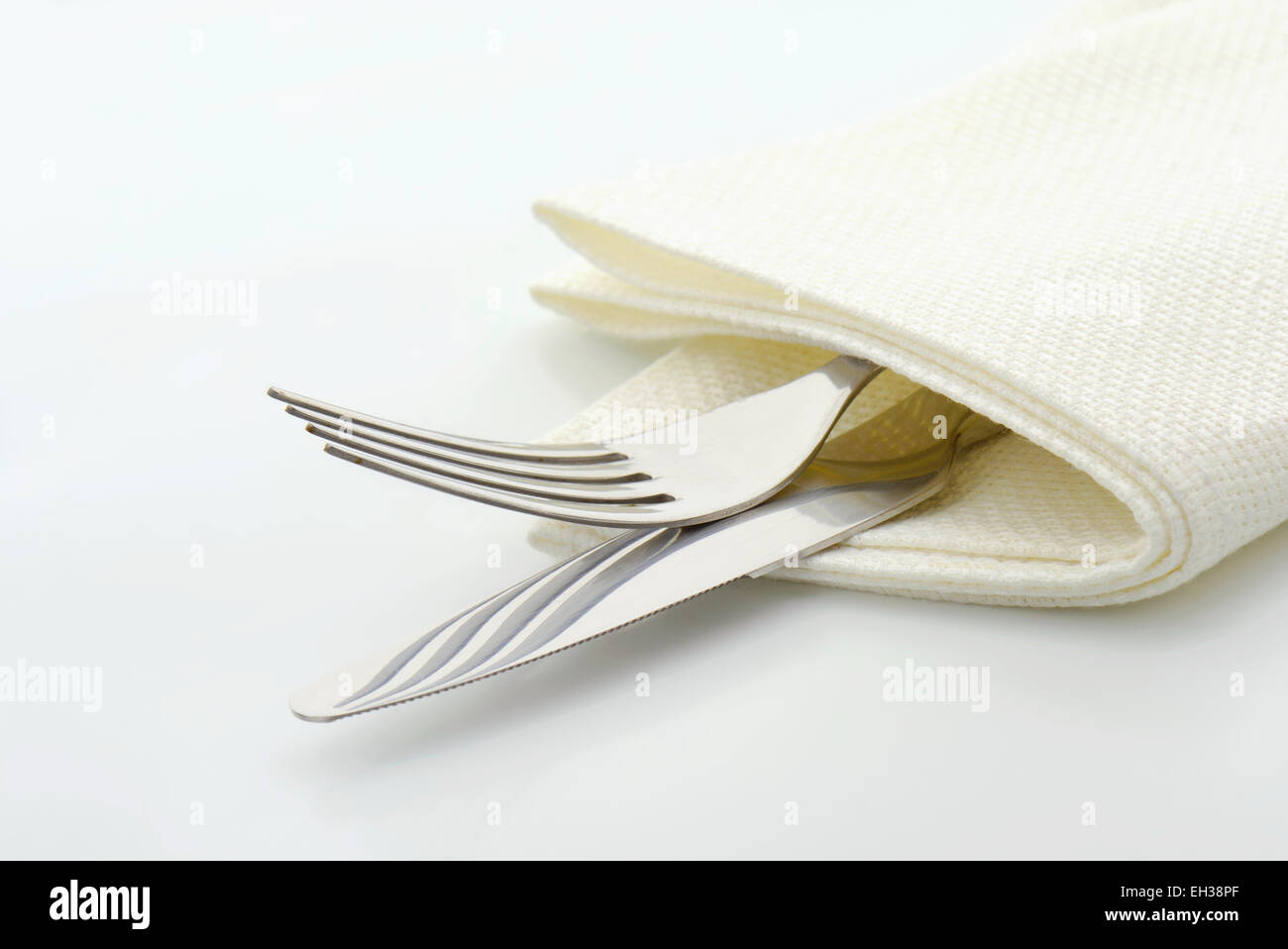Forcella in acciaio e il coltello in un tovagliolo su sfondo bianco Foto Stock