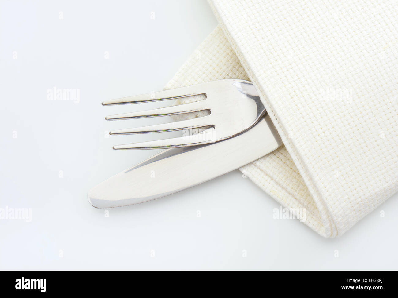 Forcella in acciaio e il coltello in un tovagliolo su sfondo bianco Foto Stock
