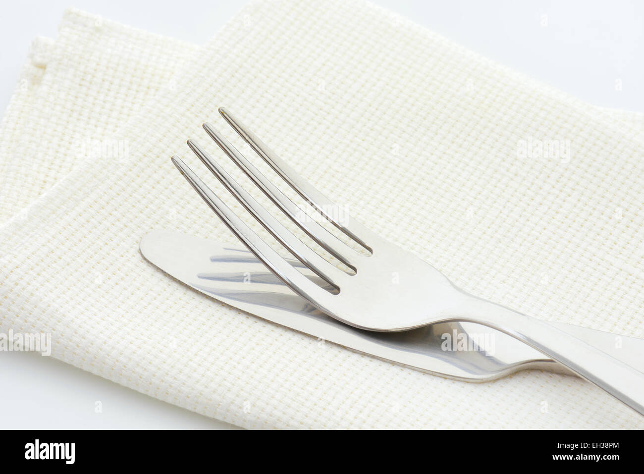 Forcella in acciaio e il coltello in un tovagliolo su sfondo bianco Foto Stock