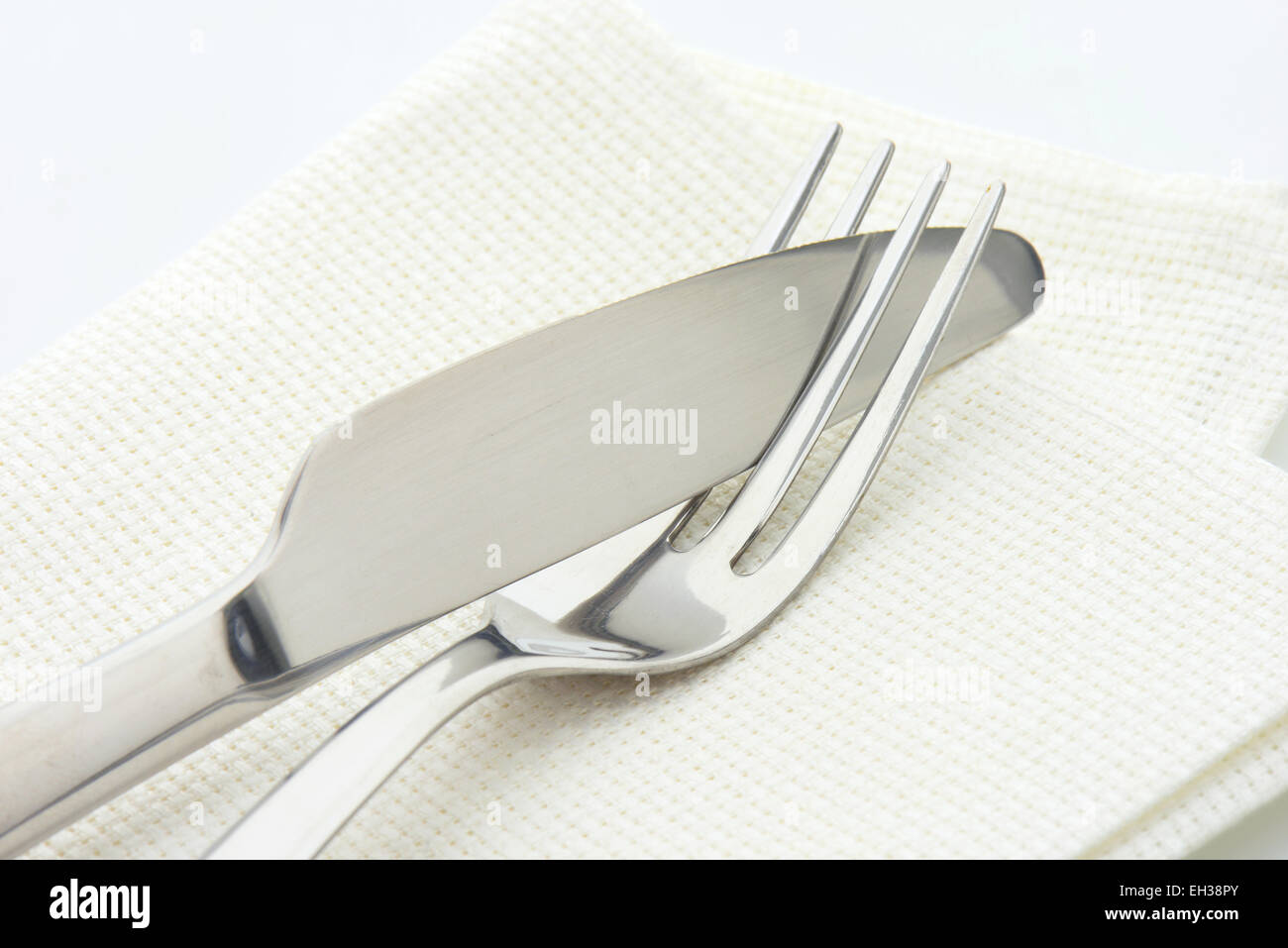 Forcella in acciaio e il coltello in un tovagliolo su sfondo bianco Foto Stock