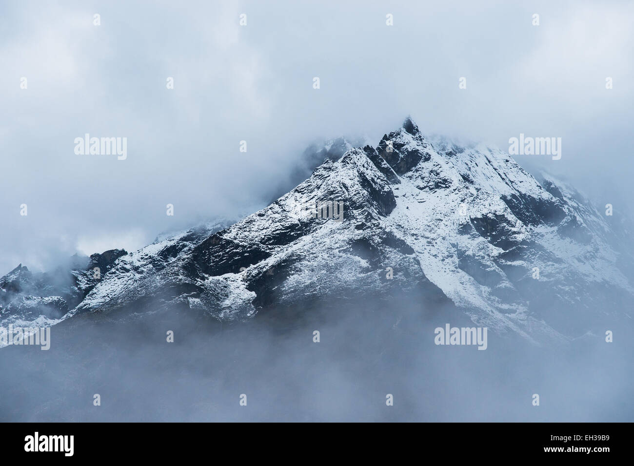 Nevicato picchi di montagna nascosti nelle nuvole in Himalaya. Viaggio in Nepal Foto Stock