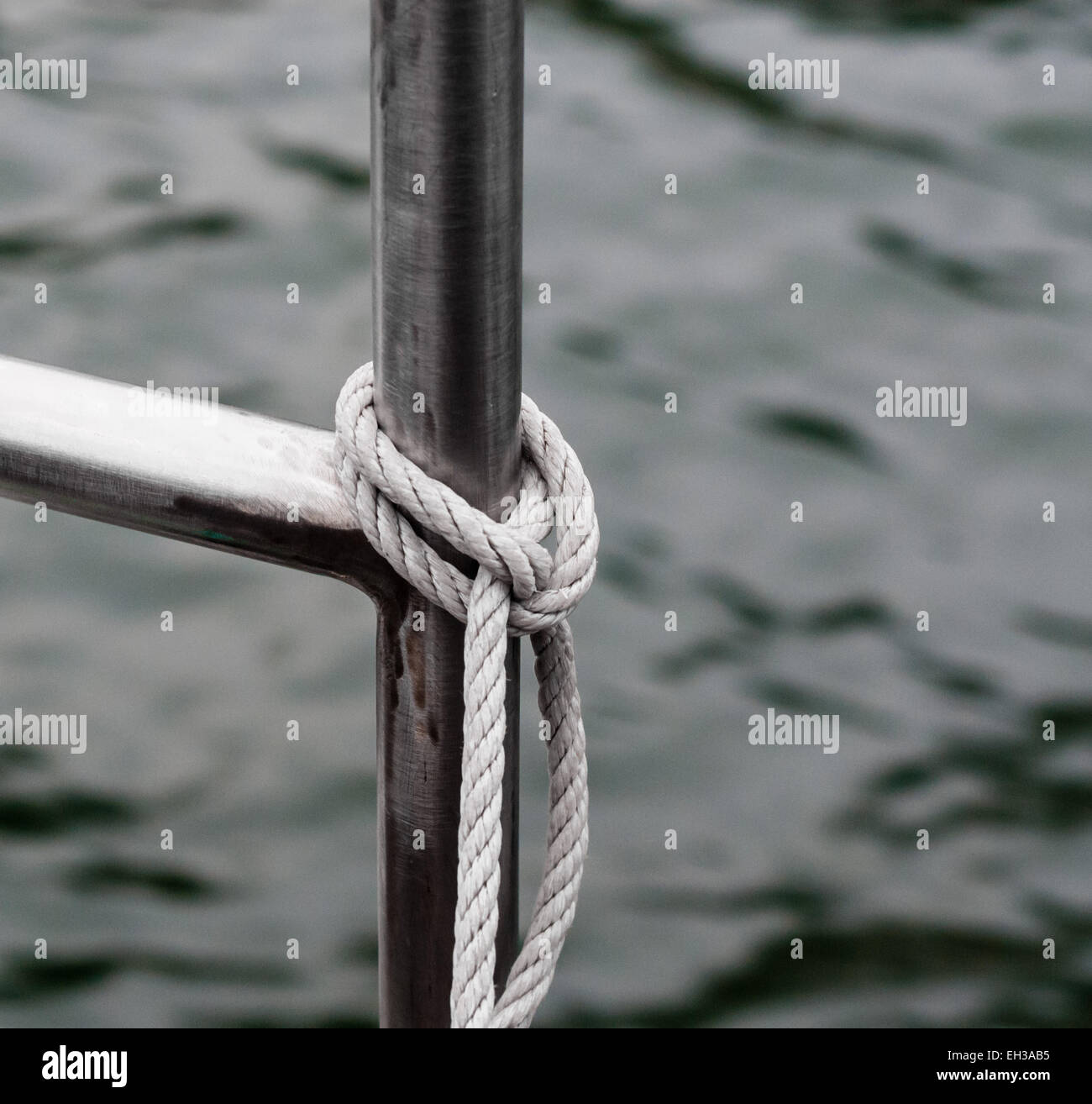 La corda legata alla ringhiera di metallo contro l'acqua. Foto Stock