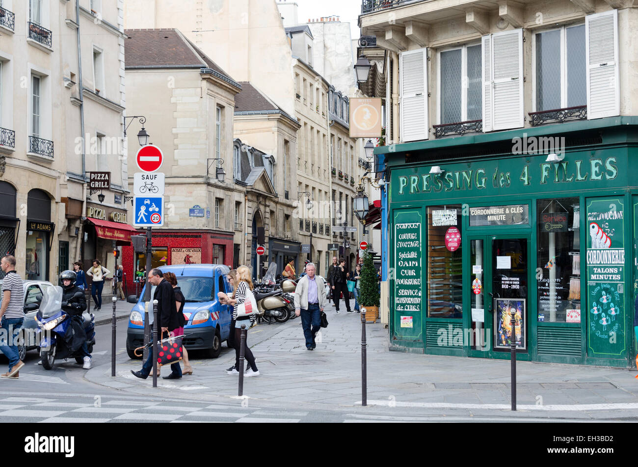 I pedoni a piedi nella parte anteriore di un servizio di lavanderia storefront su una stretta strada trafficata del quartiere Marais di Parigi, Francia. Foto Stock