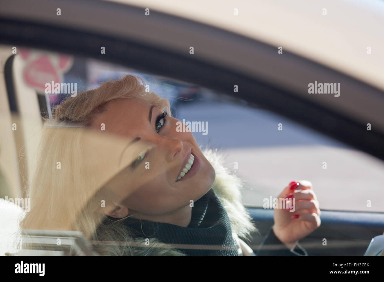 Bella donna sorridente si dalla finestra della sua automobile Foto Stock