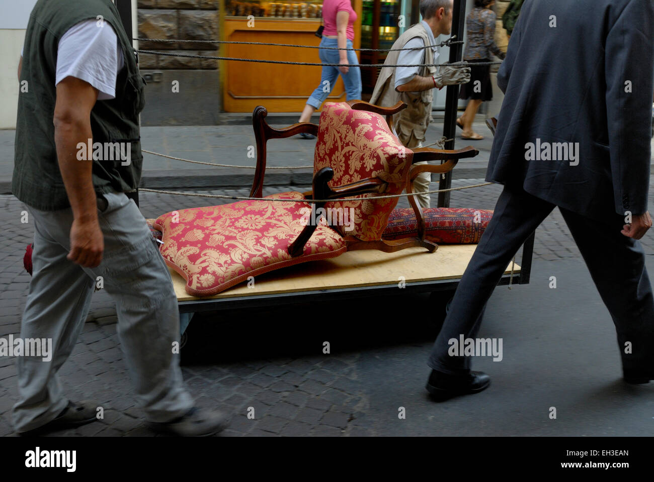 Persone trascinando un carrello con una sedia antica, Firenze, Italia Foto Stock