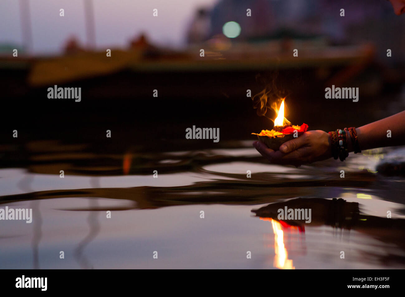 Primo piano di una mano womans mettendo a fuoco la benedizione (puja) nel fiume Gange a Varanasi al tramonto Foto Stock