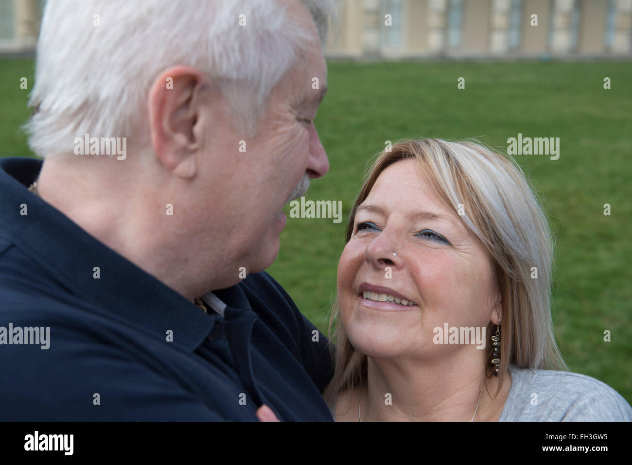 Una coppia di anziani coccolare e abbracciare mostra amore davanti al Brighton è punto di riferimento turistico il Royal Pavilion sull'erba Foto Stock