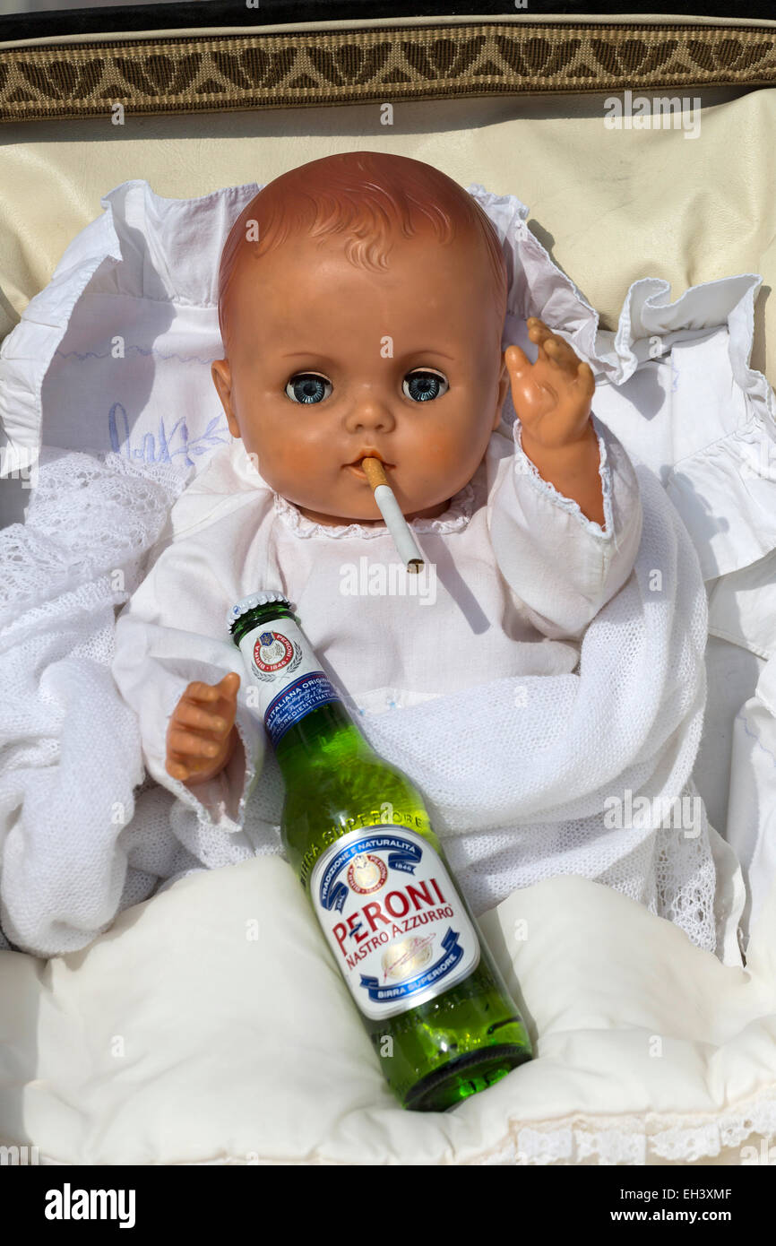Baby doll in carrozzina con la sigaretta e bottiglia di birra. Foto Stock