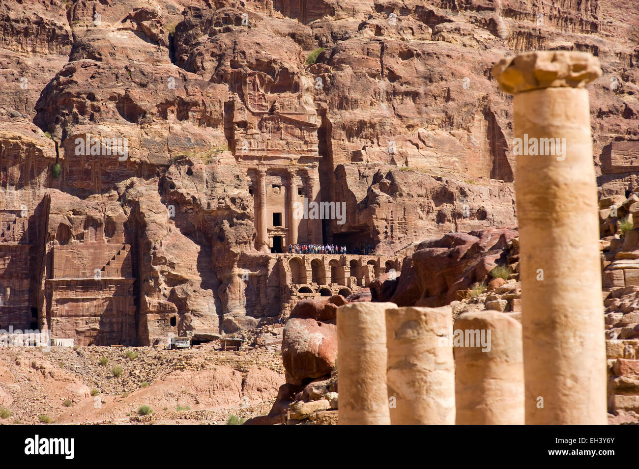 Colonne romane in primo piano e la "tomba Urn' dalle tombe reali sullo sfondo di Petra in Giordania Foto Stock