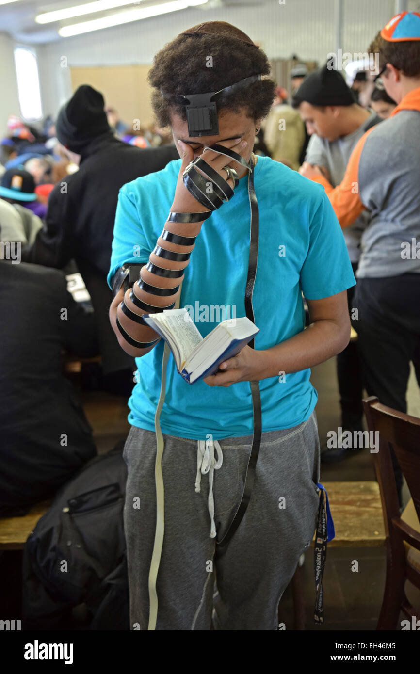 Un adolescente ebraica pregando che indossa i filatteri a Shabbaton al Ohel in Cambria Heights, Queens, a New York City. Foto Stock