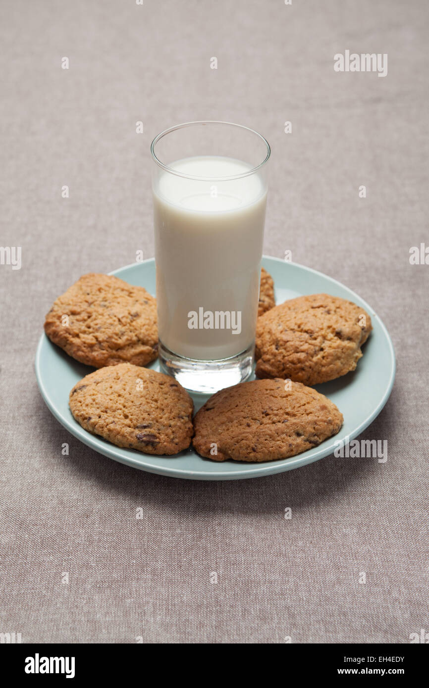 Un bicchiere di latte e biscotti su una tovaglia Foto Stock