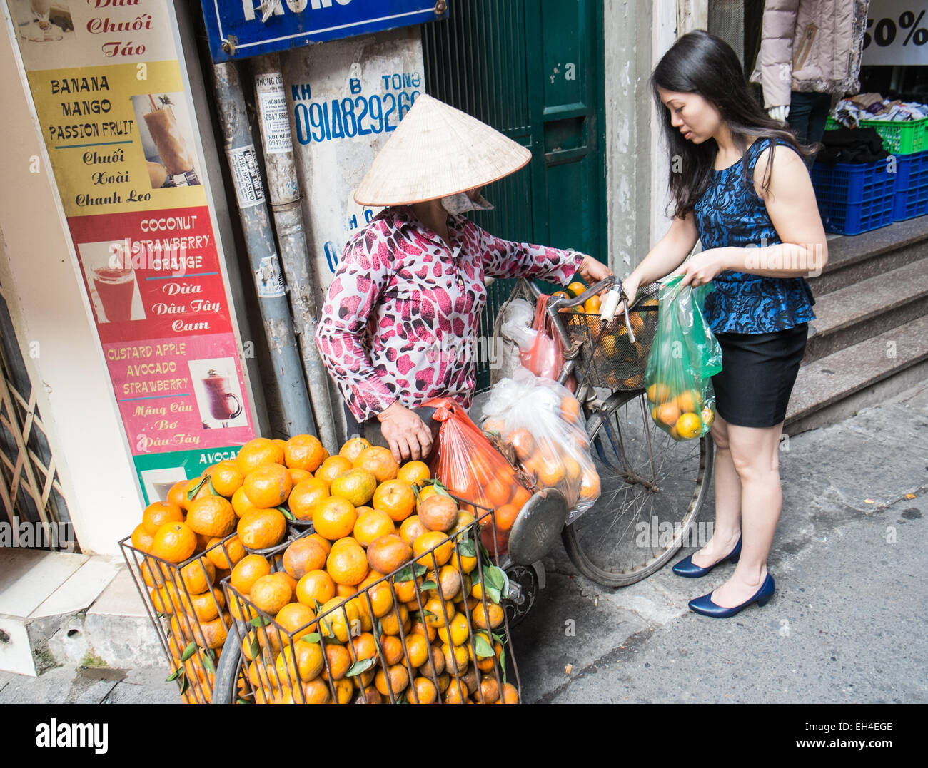 Arancione, commessa di frutta con una bicicletta a carico delle merci per la vendita, vendita di Ha Noi,Hanoi, Vietnam. Foto Stock