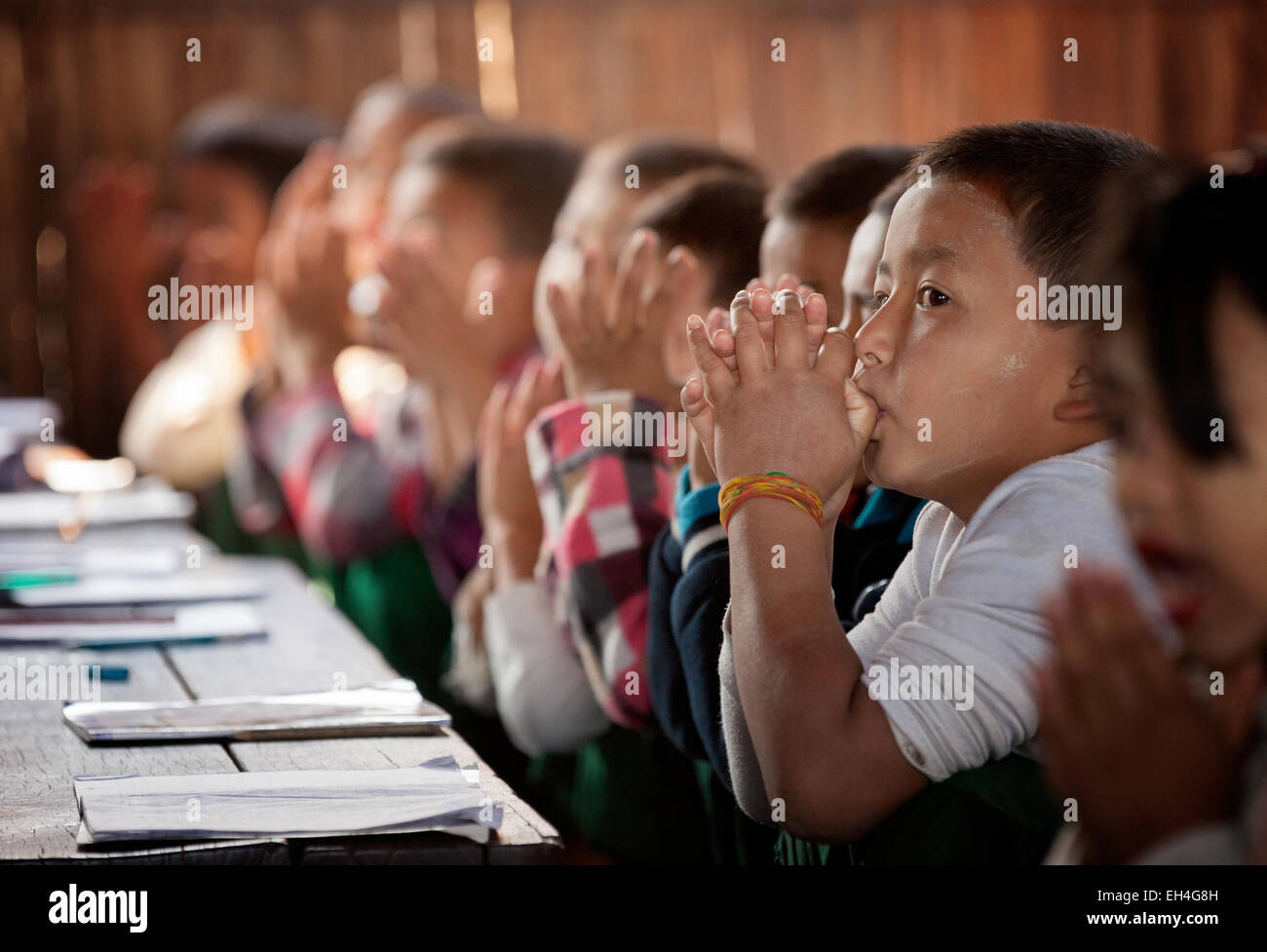 Bambini piccoli a scuola; bambini che pregano in classe all'inizio della giornata scolastica, Kar Lar Village School, Inle Lake, Myanmar Asia Foto Stock