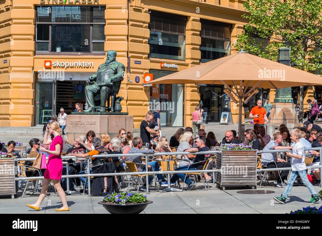 La Norvegia di Oslo, Karl Johans Gate, caffetteria terrazza Tostrup Uteservering con la statua del pittore, scrittore e giornalista norvegese Christian Krohg Foto Stock