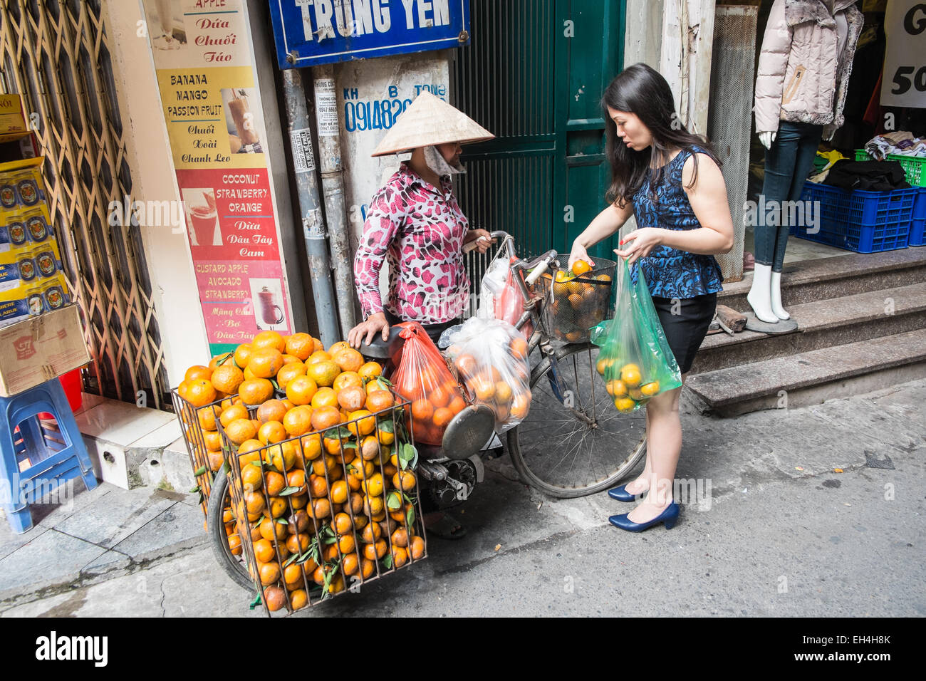 Arancione, commessa di frutta con una bicicletta a carico delle merci per la vendita, vendita di Ha Noi,Hanoi, Vietnam. Foto Stock