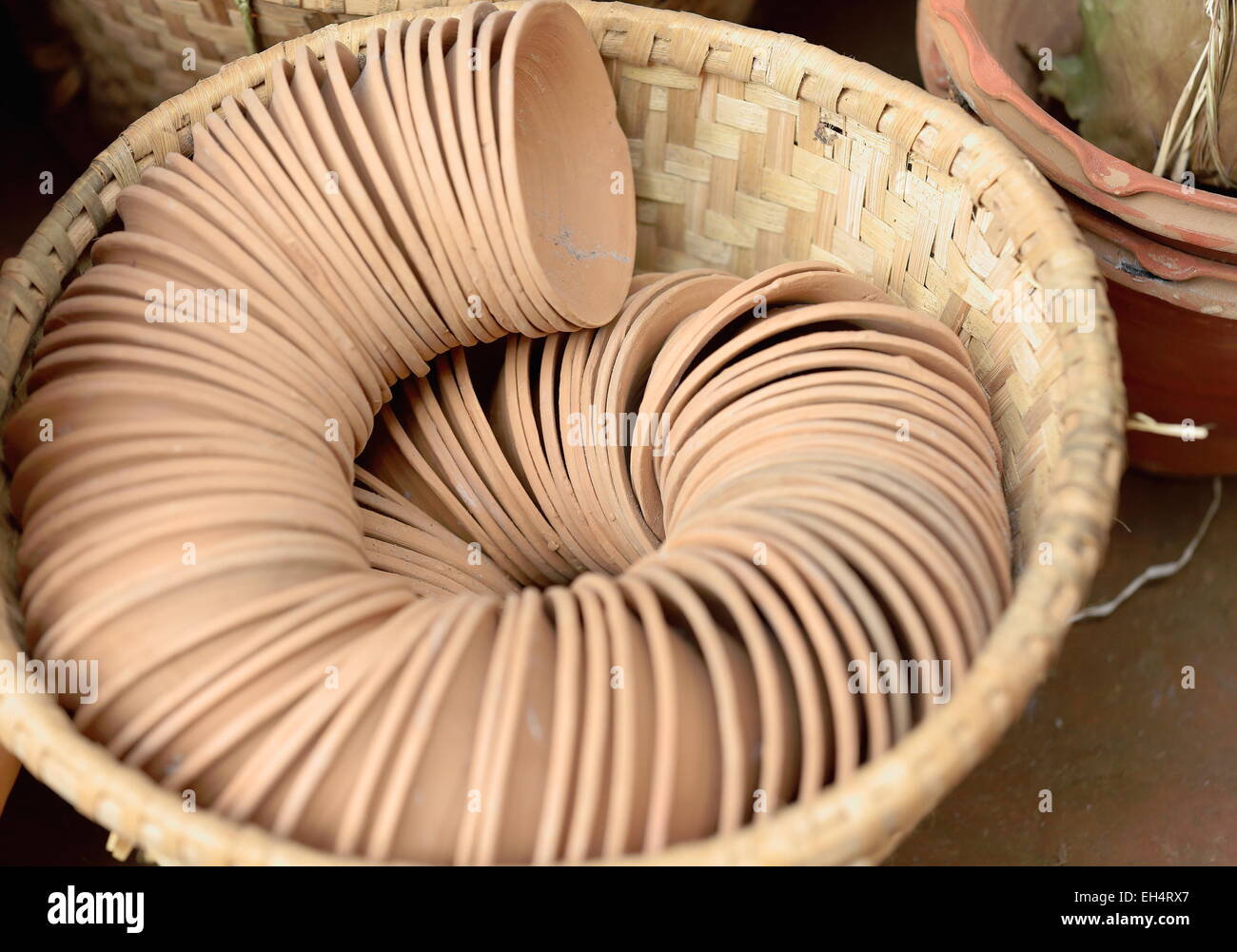 Set di piccole ciotole di terracotta collocate in una spirale di fila in un cesto di vimini sul lato esterno di un locale negozio di artigianato. Panauti-Npl. Foto Stock