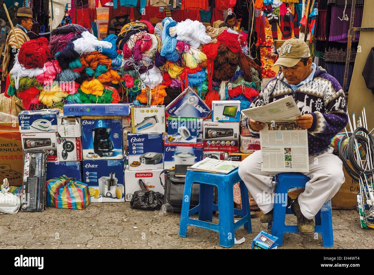 Ecuador, Cotopaxi, Zumbahua, giorno del villaggio di Zumbahua mercato, trader leggendo il giornale di fronte al suo mercato shop Foto Stock