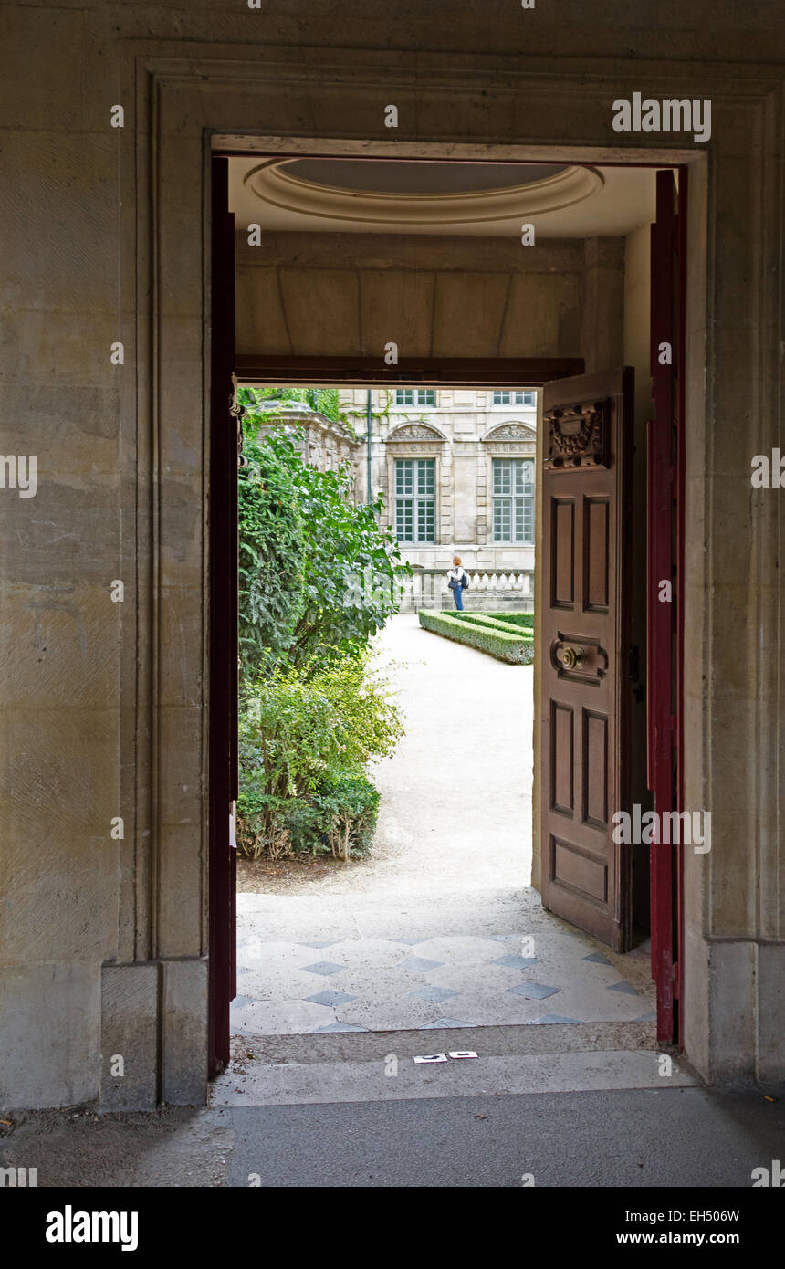 Un di legno intagliato si apre la porta dal porticato della Place des Voges nel giardino dell'Hôtel Sully, Parigi. Foto Stock