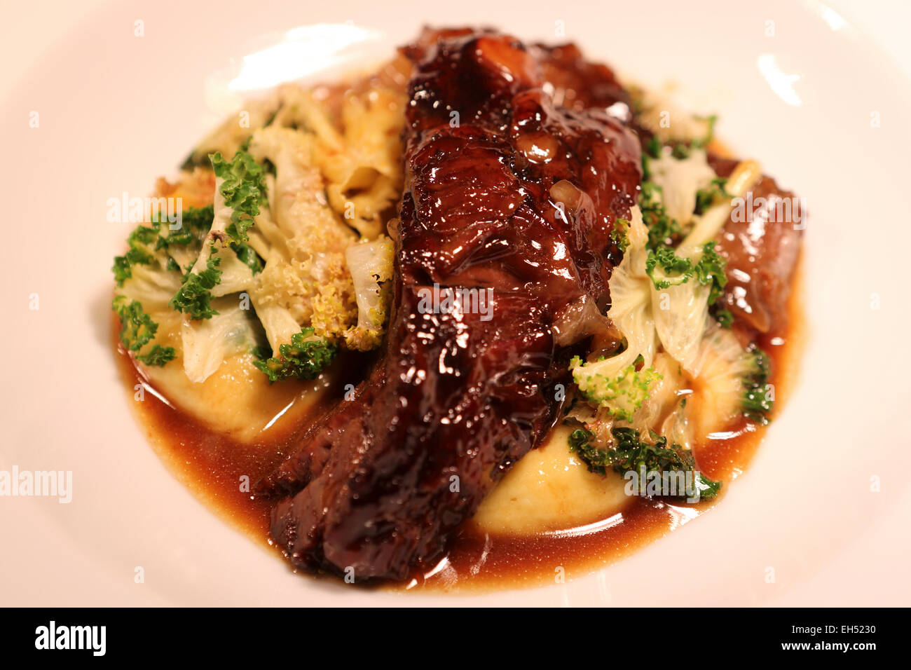 Una piastra di slow manzo cotto guance, savora mash, rainbow cavolo rapa e paglia. Foto Stock