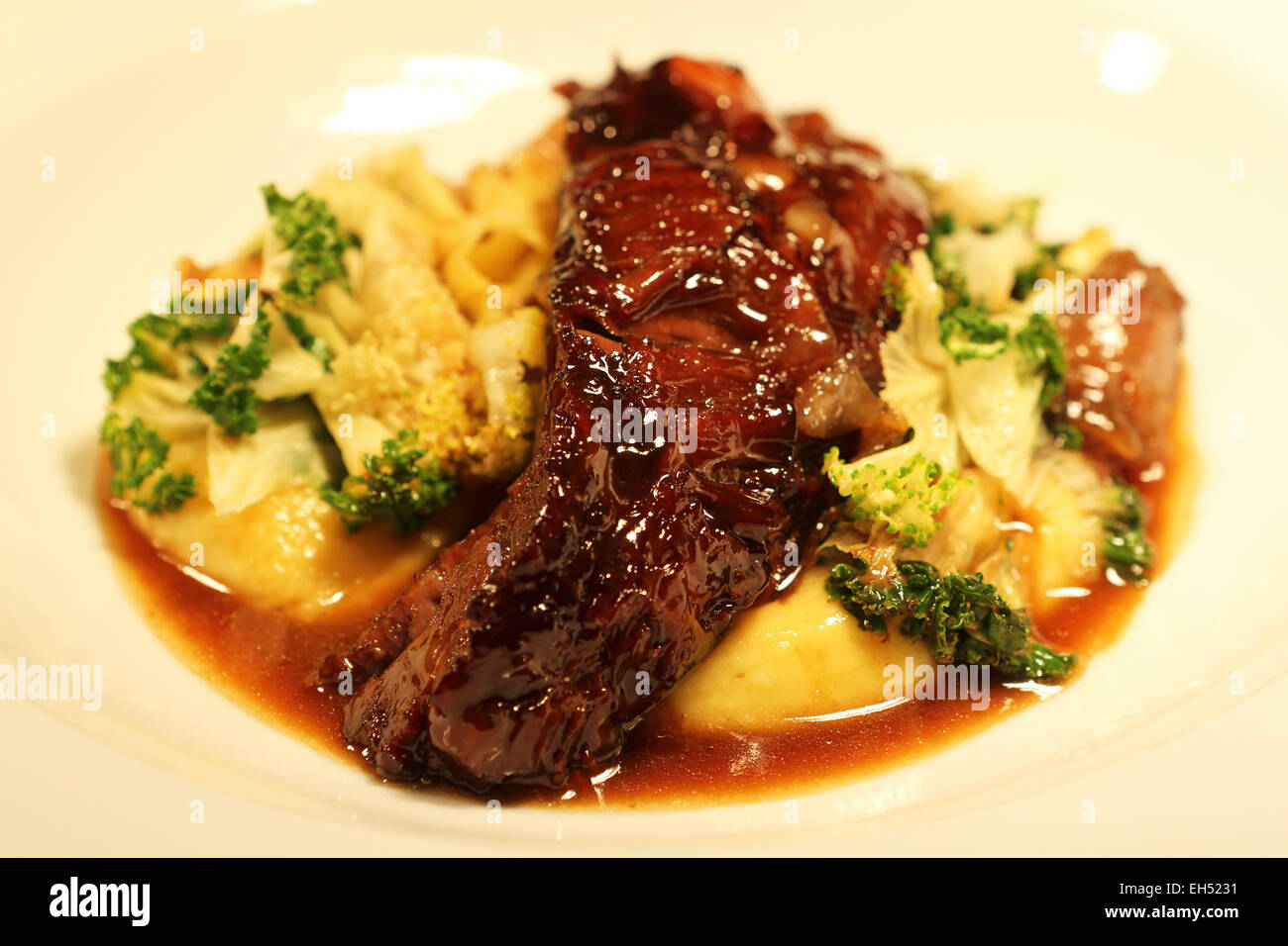 Una piastra di slow manzo cotto guance, savora mash, rainbow cavolo rapa e paglia. Foto Stock