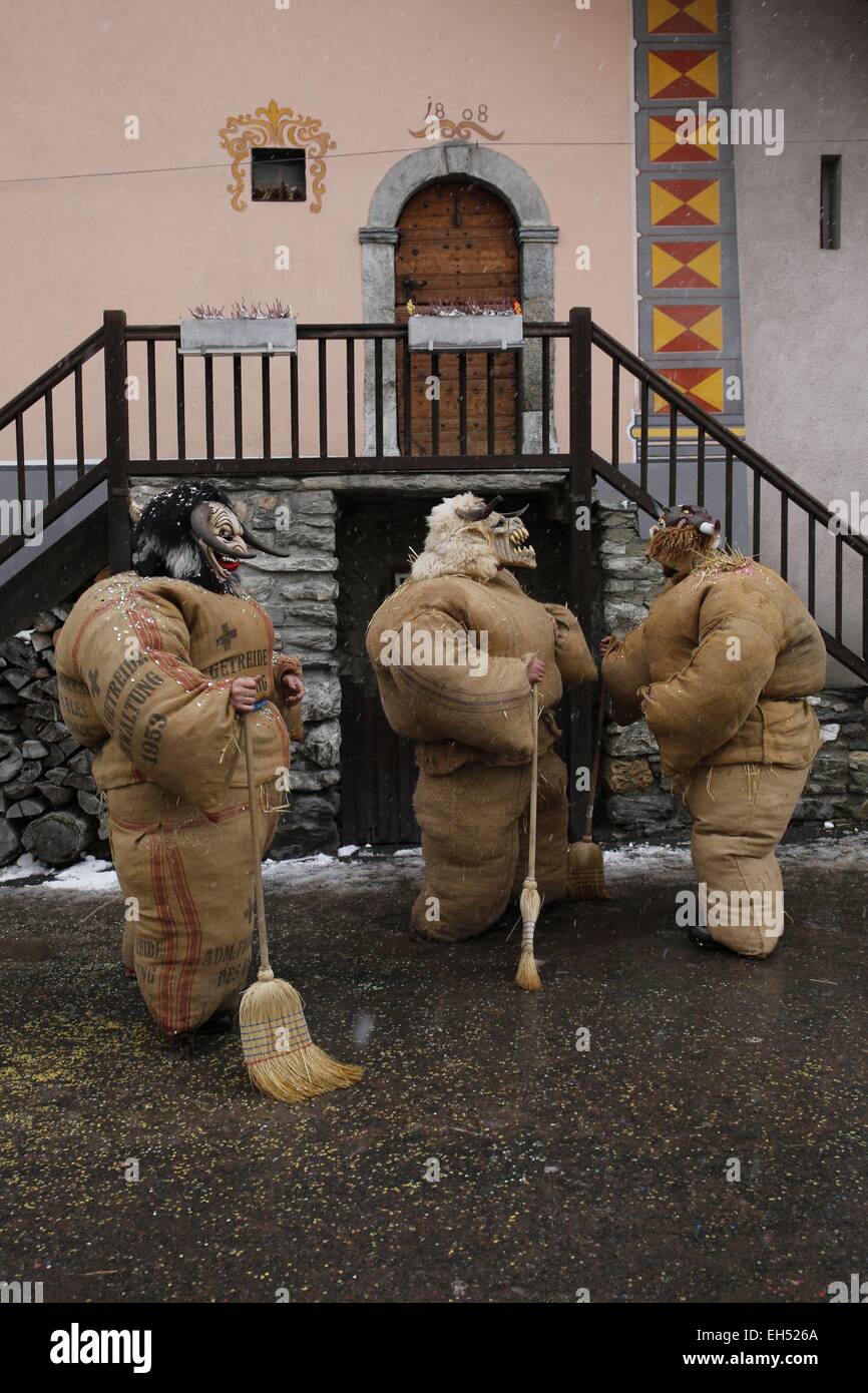 La Svizzera nel canton Vallese, Val d'Herens, Evolene, Carnaval, preparazione del empailles (giovani uomini vestiti con vecchi sacchetti ripieni di circa 50 kg di paglia) e indossando un localmente in legno intagliato che rappresenta la maschera mitico e spesso afraying animali Foto Stock