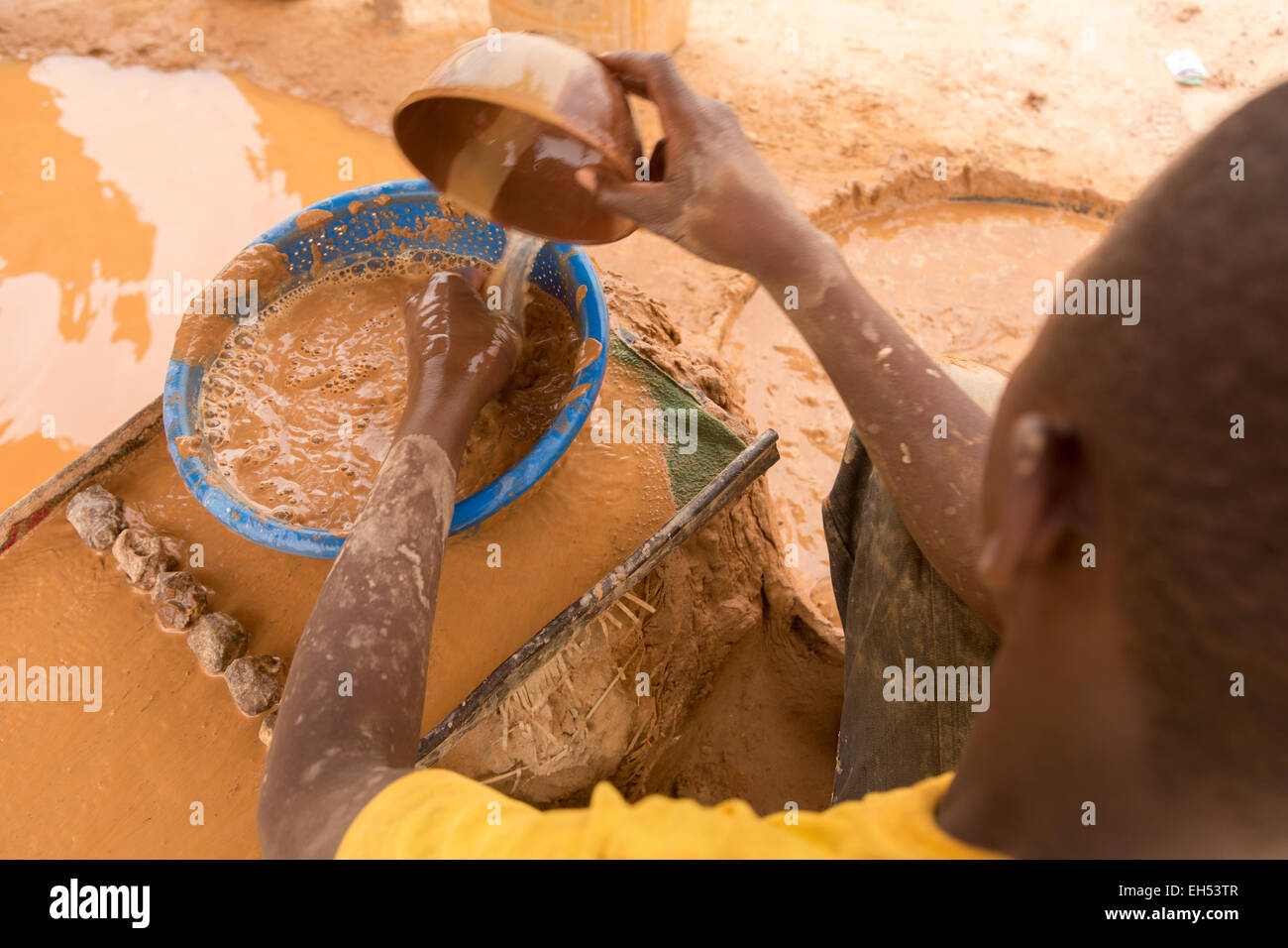 KOMOBANGAU, NIGER, 15 maggio 2012 il 15 Maggio 2012: un minatore lava la massa di basso grado di minerale estratto stiny frammenti di oro Foto Stock