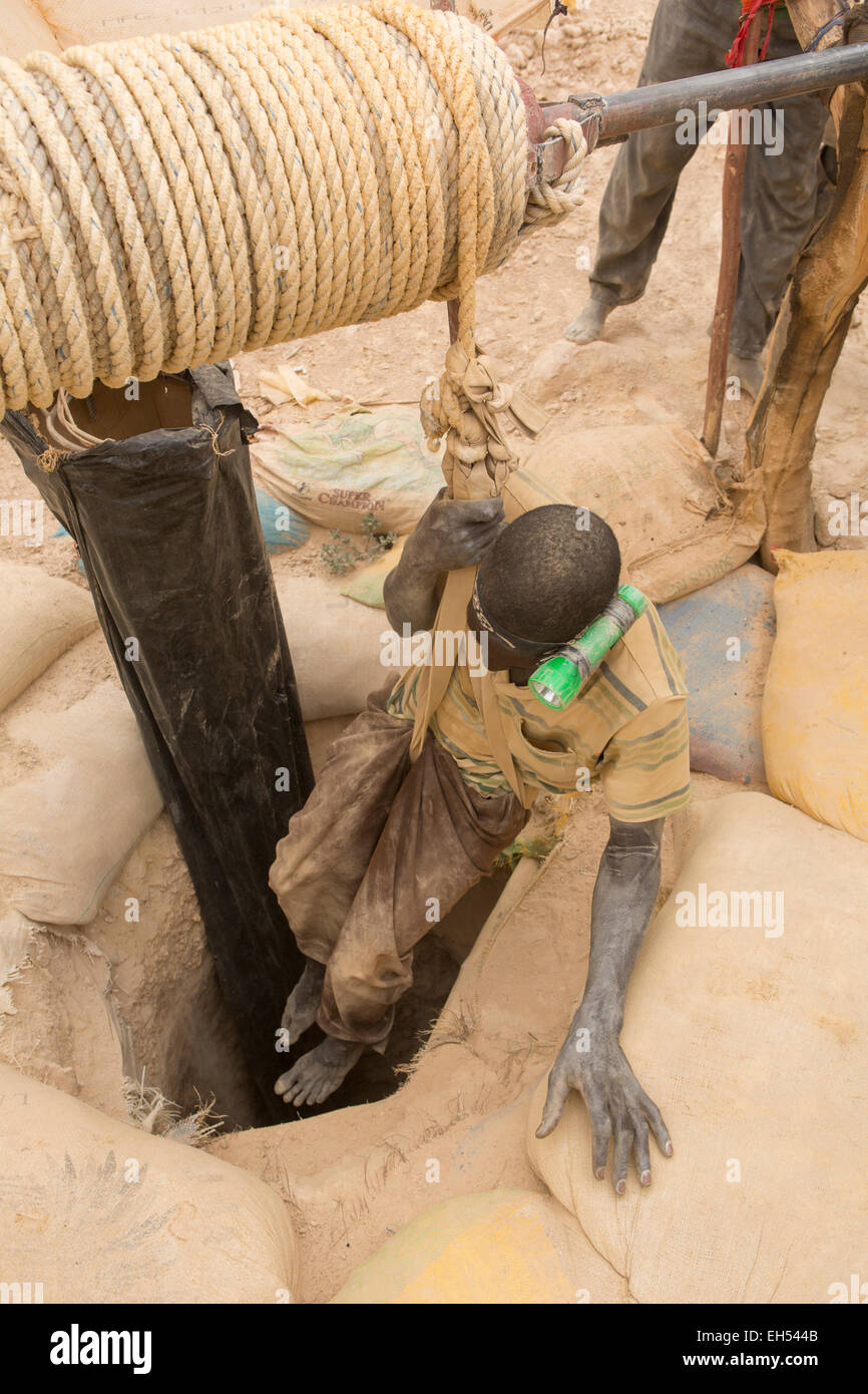 KOMOBANGAU, NIGER, : un minatore mette su una imbracatura per essere abbassato l'albero di ingresso di un grezzo miniera d'oro. Foto Stock