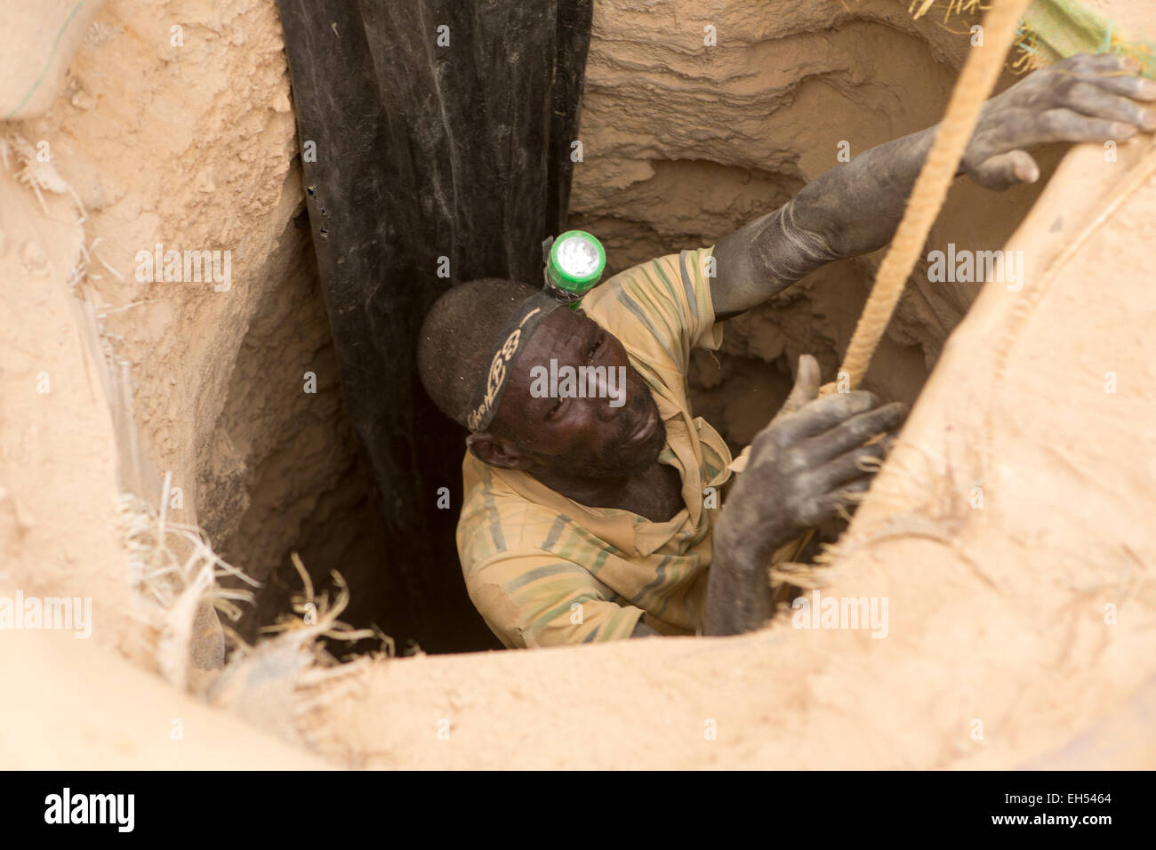 KOMOBANGAU, NIGER, : un minatore mette su una imbracatura per essere abbassato l'albero di ingresso di un grezzo miniera d'oro. Foto Stock