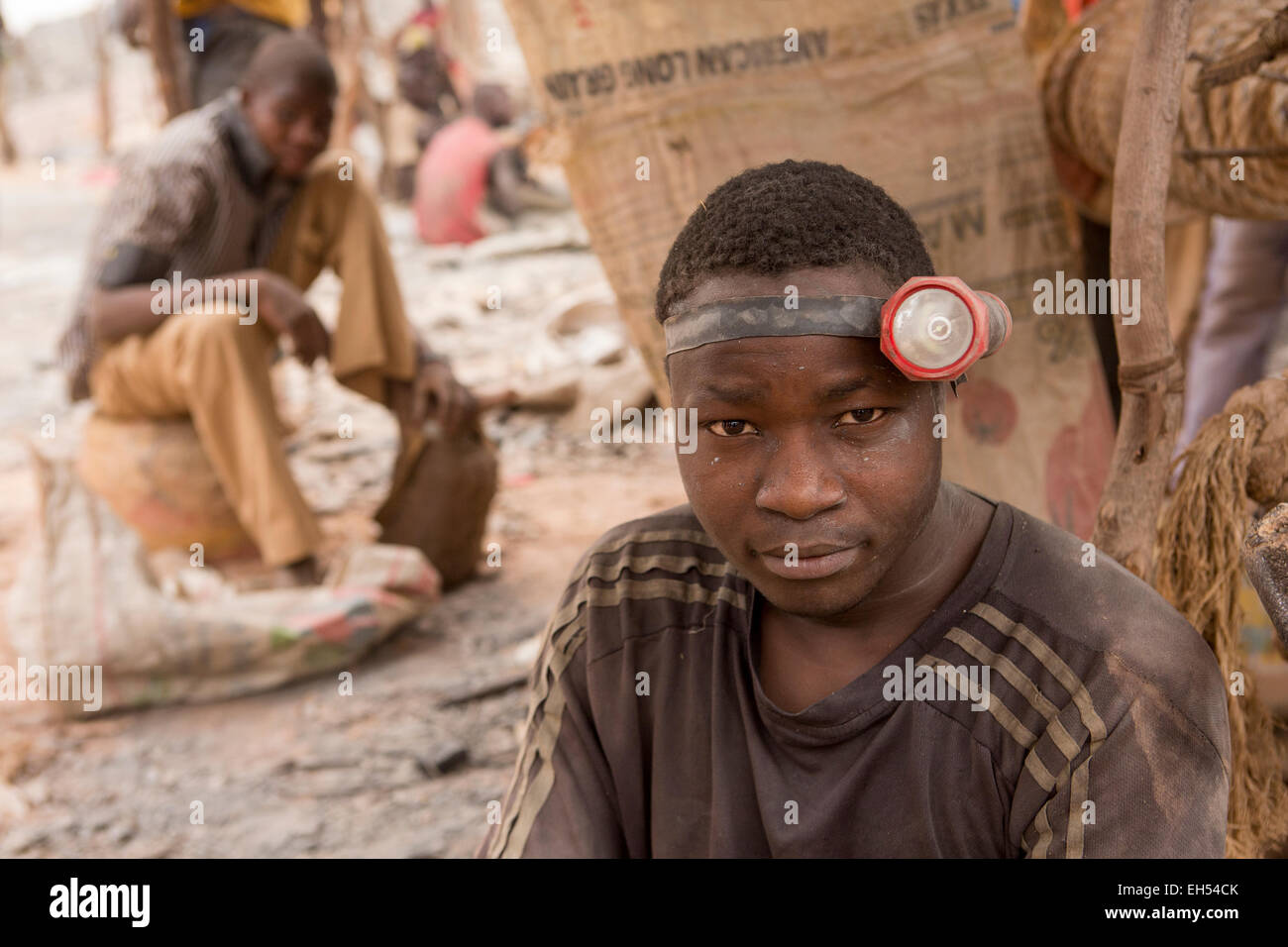 KOMOBANGAU, NIGER, : un minatore che indossa la sua torcia da testa accanto alla verticale di albero di entrata di loro oro grezzo di miniera. Foto Stock