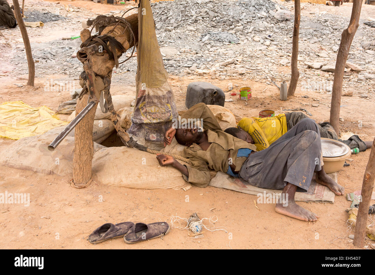 KOMOBANGAU, NIGER, : un minatore esausto dorme accanto l'entrata verticale albero del loro grezzo miniera d'oro. Foto Stock