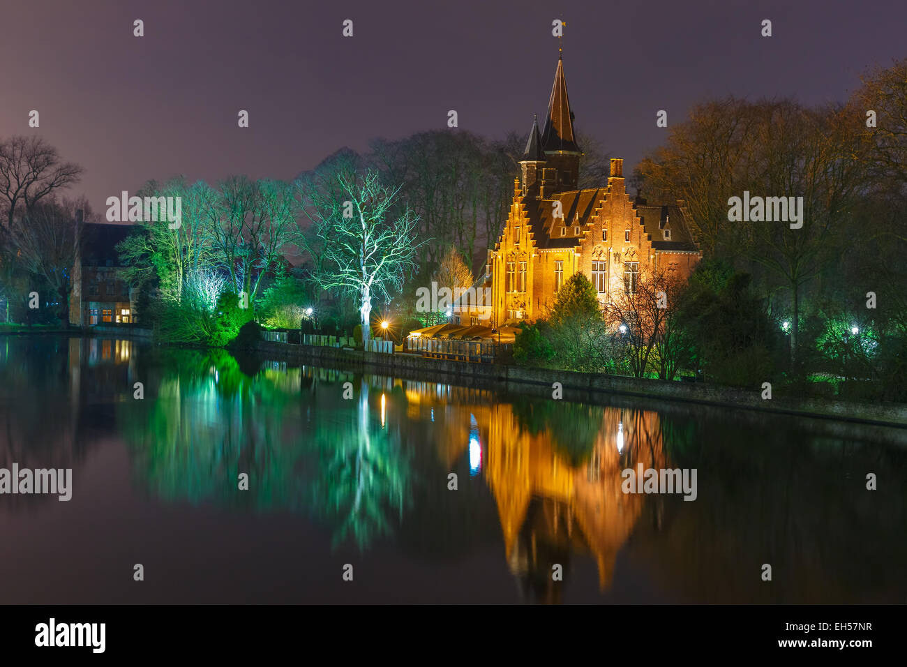 Fiabesco paesaggio notturno con una casa medievale sul lago Minnewater a Bruges, Belgio Foto Stock