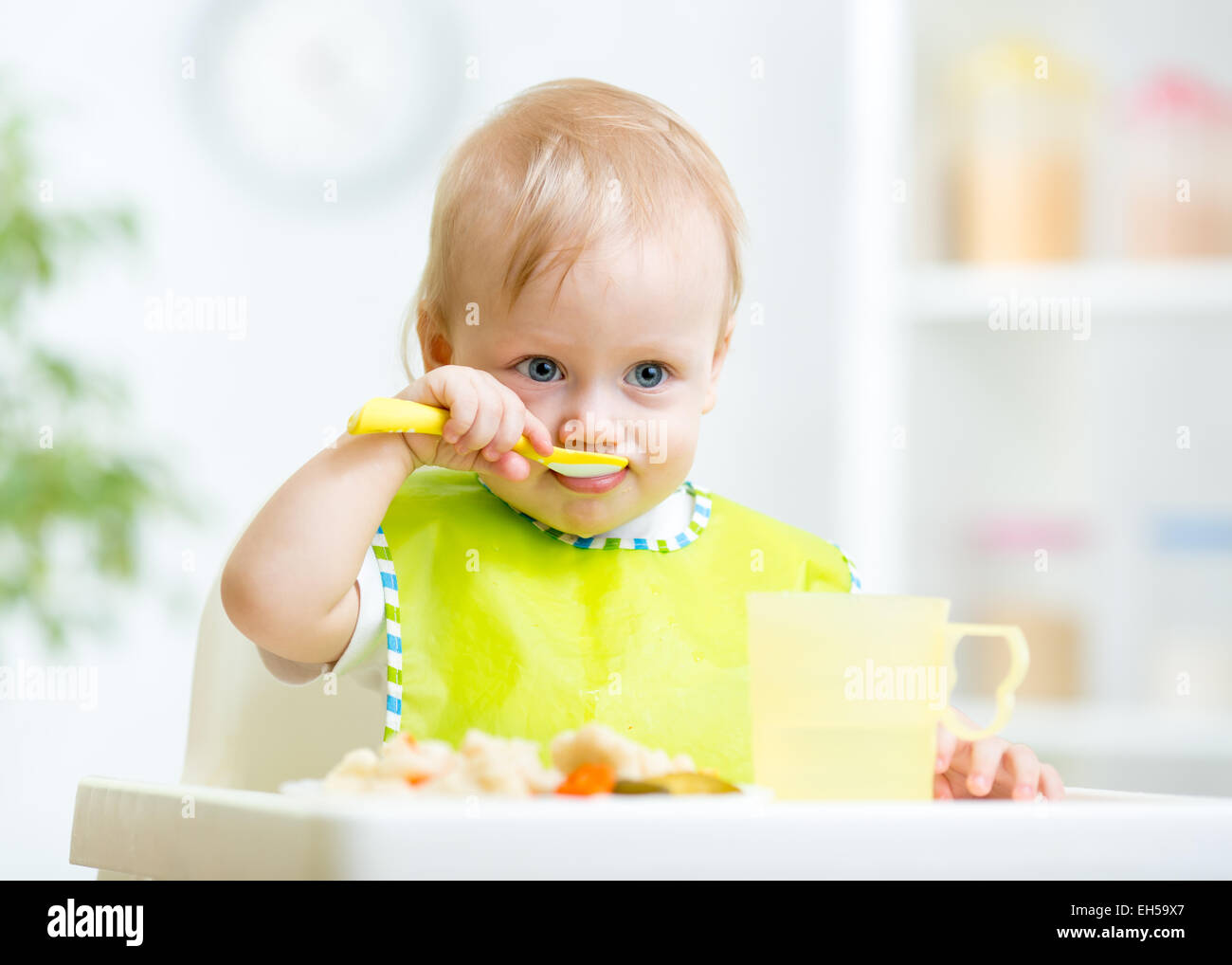 Baby bambino seduto in poltrona con un cucchiaio Foto Stock