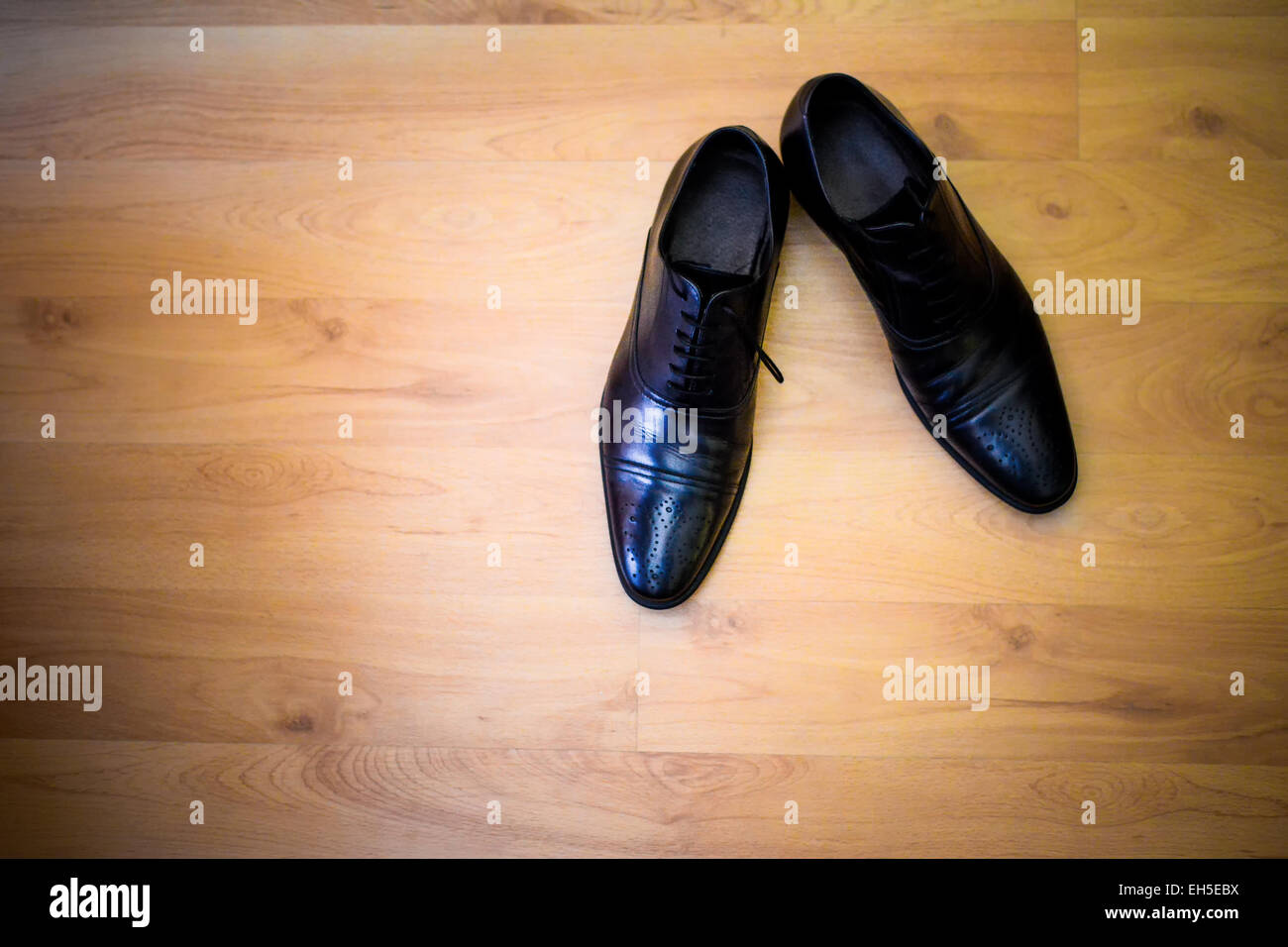 Nero scarpe sposo seduto su pavimenti in legno duro Foto Stock
