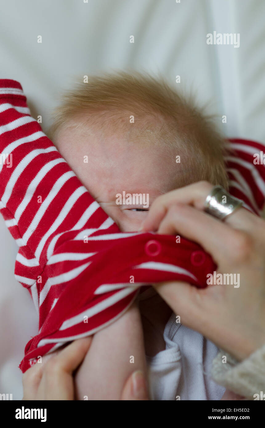Una 10-week-old baby boy infelice e irritato per essere vestito. Foto Stock
