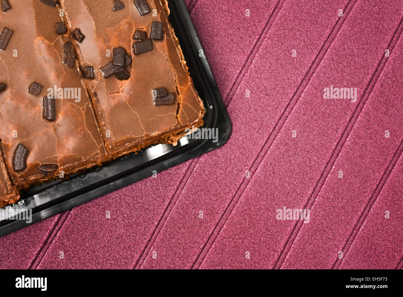 Torta al cioccolato collocato in un nero vassoio di plastica con sfondo viola Foto Stock