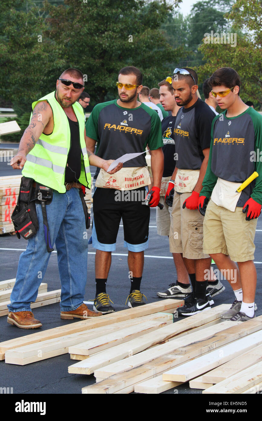 Wright State University gli studenti la selezione di pretaglio legname per la costruzione di una sezione di parete. Habitat for Humanity parcheggio costruire. Buildi Foto Stock