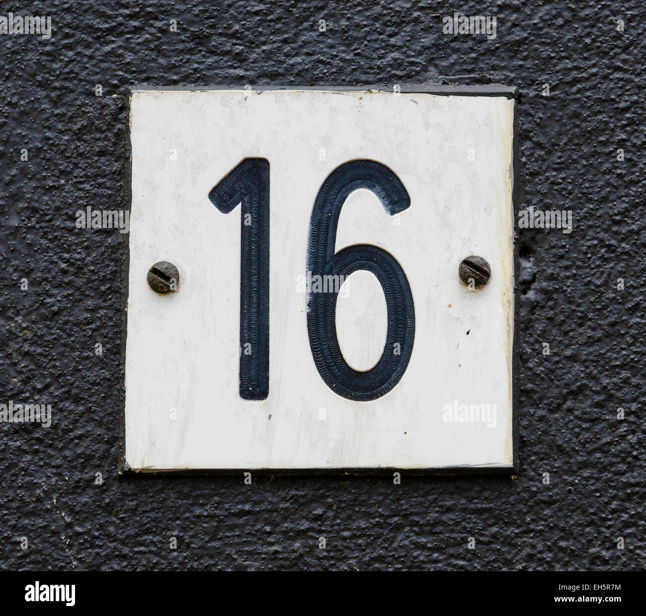 Segno del numero civico 16 in caratteri neri su una parete nera. Foto Stock