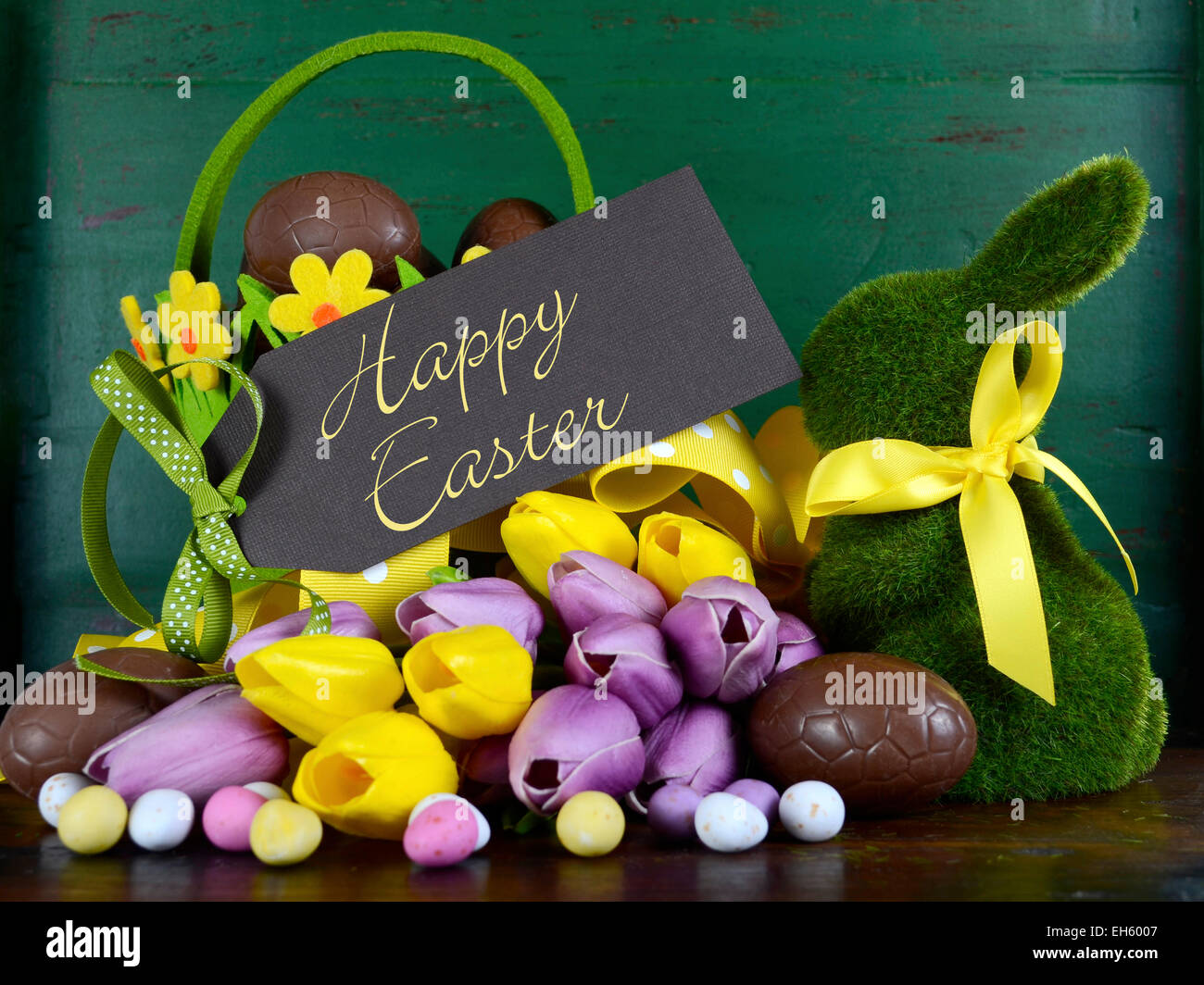 Felice Pasqua verde erba moss bunny coniglio con cesto di uova di cioccolato e tulipani a molla contro un legno verde dello sfondo. Foto Stock