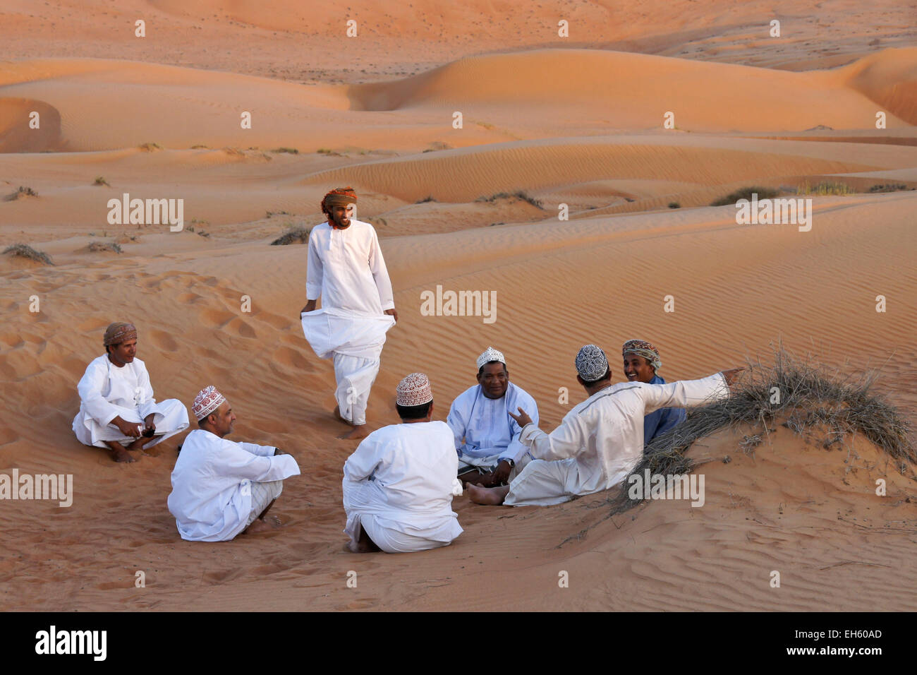 Gruppo di uomini socializzare in mezzo alle dune di sabbia Sharqiya (Wahiba Sands), Oman Foto Stock