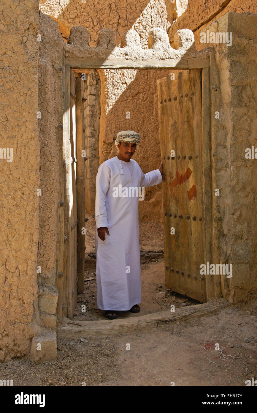 L uomo nella porta del vecchio edificio mudbrick, Al-Hamra, Oman Foto Stock