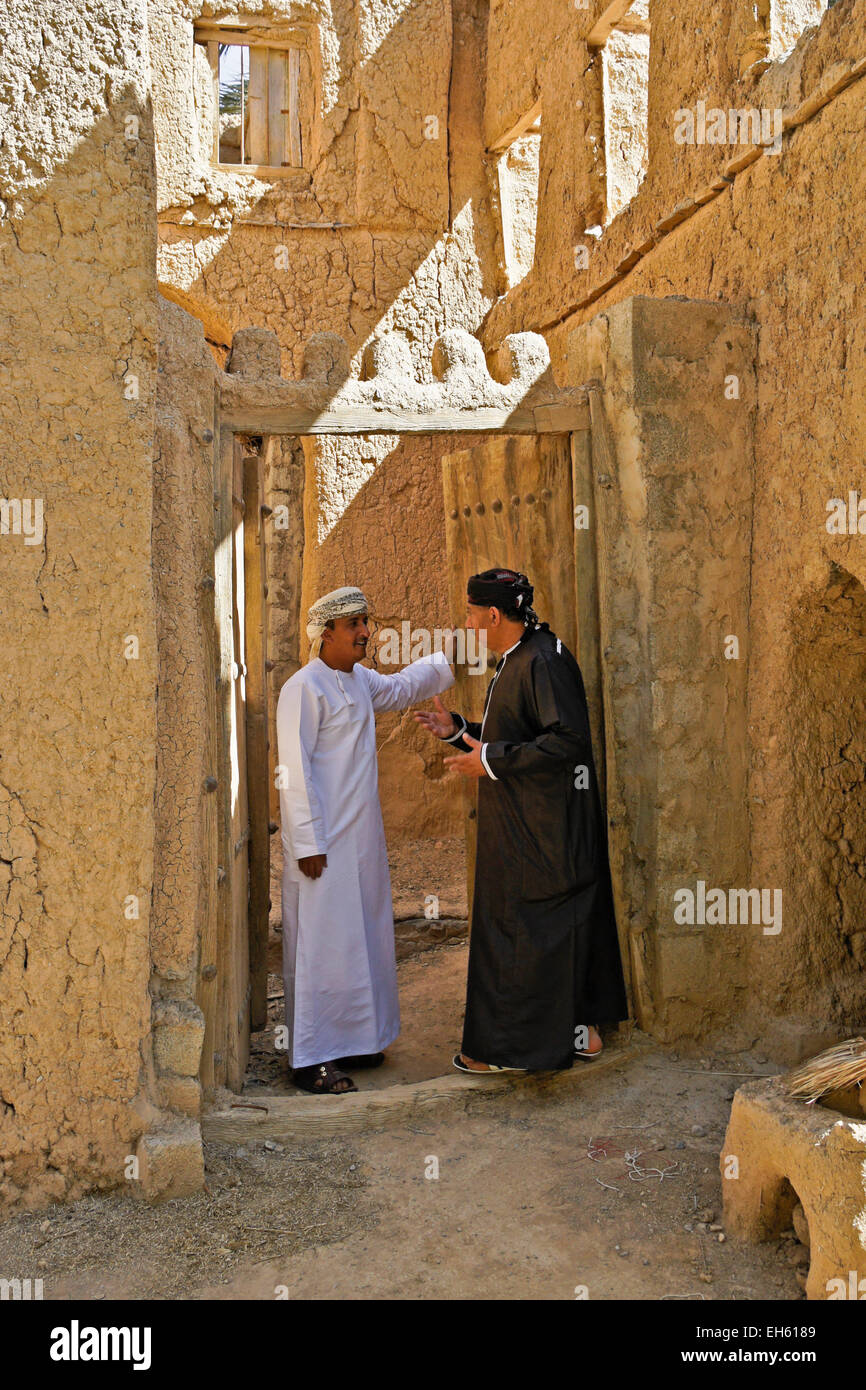 Gli uomini nella porta del vecchio edificio mudbrick, Al-Hamra, Oman Foto Stock
