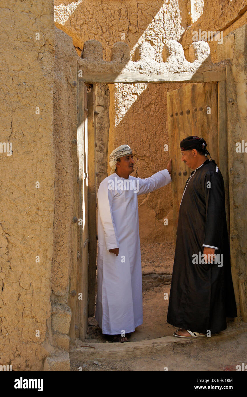Gli uomini nella porta del vecchio edificio mudbrick, Al-Hamra, Oman Foto Stock